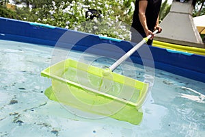 Young man cleaning a portable swimming pool