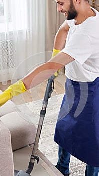 Young man Cleaning sofa With Vacuum Cleaner in leaving room At Home