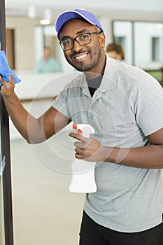 young man cleaning window in office