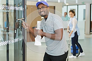 young man cleaning window in office