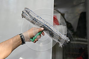 A young man cleans and polishes windows with a sponge