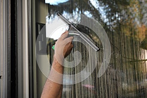 A young man with cleans and polishes windows with a sponge