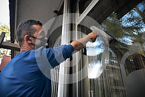 A young man with cleans and polishes windows with a sponge