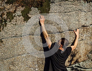 Young man climber climb on rock in small crack stone