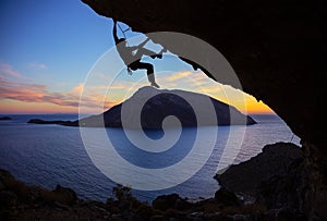 Young man climbing along roof in cave