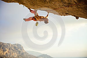 Young man climbing on ledge in cave before sunset
