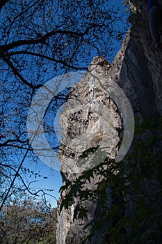 Young man climbing on a limestone wall with wide valley on the background