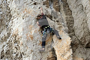 Young man climbing on a limestone wall with wide valley on the background