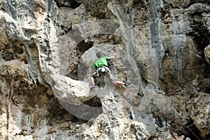 Young man climbing on a limestone wall with wide valley on the background