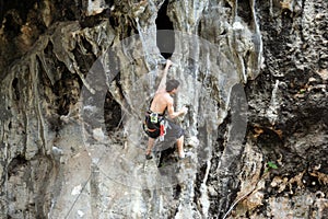 Young man climbing on a limestone wall with wide valley on the background