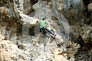 Young man climbing on a limestone wall with wide valley on the background