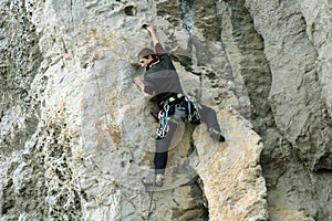 Young man climbing on a limestone wall with wide valley on the background