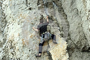 Young man climbing on a limestone wall with wide valley on the background