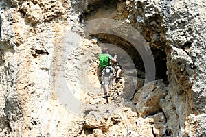 Young man climbing on a limestone wall with wide valley on the background