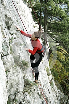 Young man climbing on a limestone wall with wide valley on the background