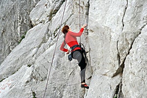 Young man climbing on a limestone wall with wide valley on the background