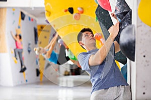 Young man climbing on rock-climbing wall