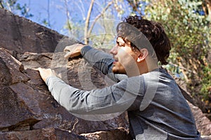 Young man climbing rock mountain on sunny day