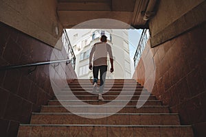 Young man climbing stairs in pedestrian subway