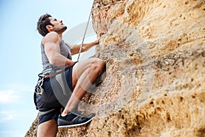 Young man climbing a steep wall in mountain