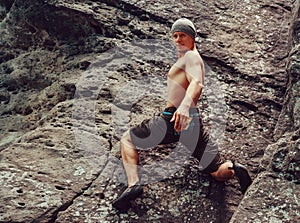 Young man climbing on stone rock, bouldering