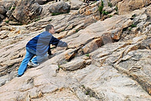 Young man climbing treacherous mountain cliff