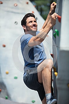 young man climbing wall rock outdoors