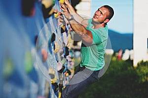Young man climbing wall rock outdoors