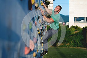 Young man climbing wall rock outdoors