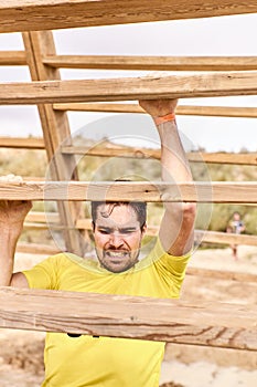 Young man climbing a wooden ladder in a Spartan race