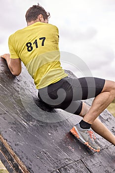 Young man climbing a wooden wall in a Spartan race