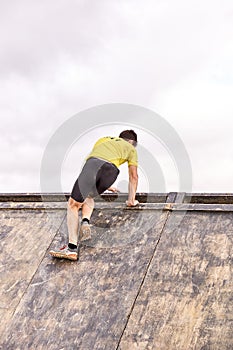 Young man climbing a wooden wall in a Spartan race