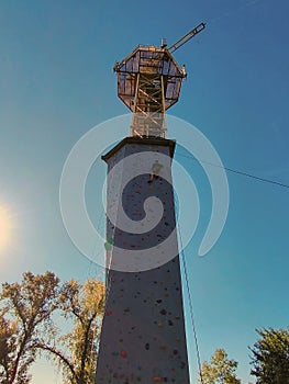 A young man climbs the wall for climbing in special equipment. View from below