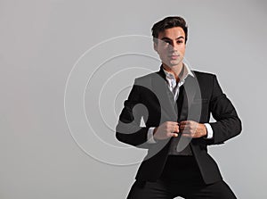 Young man closing his tuxedo coat and looks away