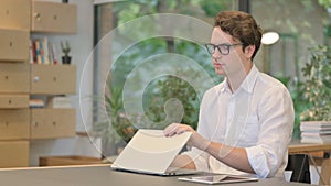 Young Man Closing Laptop and Leaving Modern Office