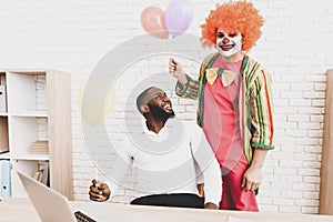 Young Man in Clown Costume with Baloons in Office.