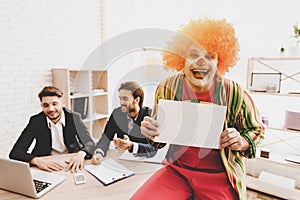 Young Man in Clown Costume on Meeting in Office.