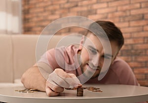 Young man with coins at home. Saving money