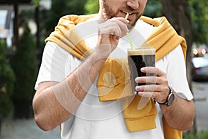 Young man with cold kvass outdoors, closeup. Traditional Russian summer drink