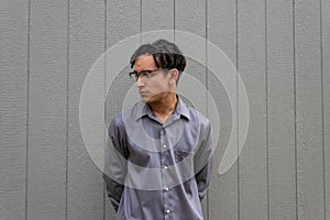 Young man in collared shirt, serious demeanor, profile view with glasses and natural black hair in dreads