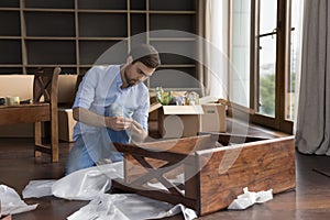 Young man collects wooden nightstand on relocation day