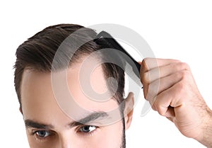 Young man with comb on white background. Hair loss problem
