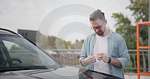 Young man comes to car and finds Parking Ticket Or Fine On Car Windshield