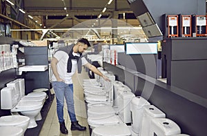 Young man comes to the store to buy a modern ceramic flush toilet for his new house