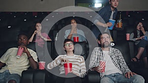 Young man coming to cinema late holding food and drink disturbing people