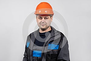 A young man construction worker in a safety helmet and work uniform on a white background