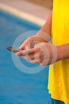 young man consulted the mobile phone by the pool
