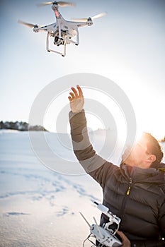 Young man controlling his drone in snowy outdoors