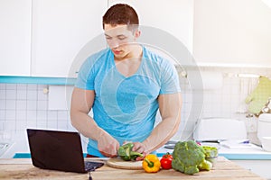 Young man cooking healthy meal vegetables computer internet eating