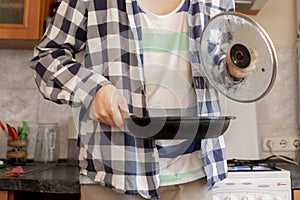 young man cooking healty meal in a pan at the kitchen, food preparation leisures